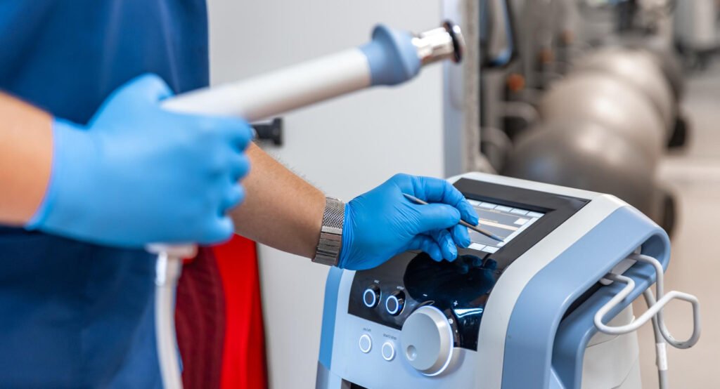 A person in blue gloves operates an electric machine in a medical setting, likely an orthopedic doctor's office.jpg